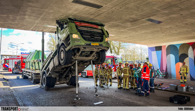 Vrachtwagen rechtop vast onder viaduct, chauffeur bekneld