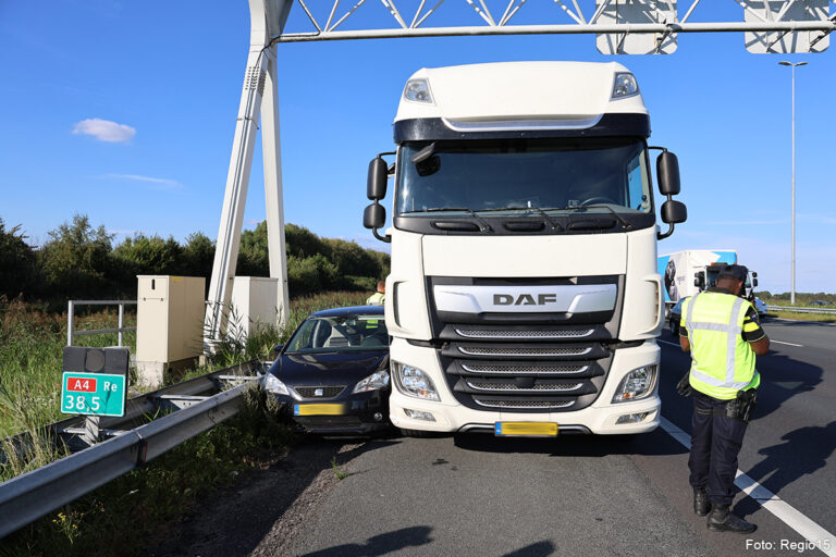 Auto klem tussen vrachtwagen en vangrail op A4