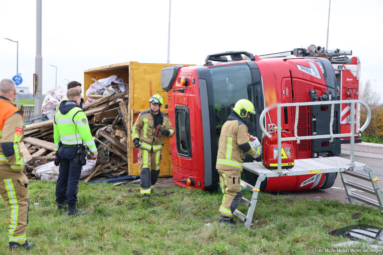 Vrachtwagen met afval kantelt op rotonde N232: chauffeur bekneld geraakt
