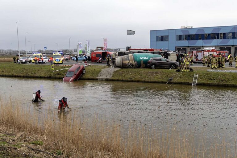 Gekantelde cementwagen duwt auto in het water in Aalsmeer