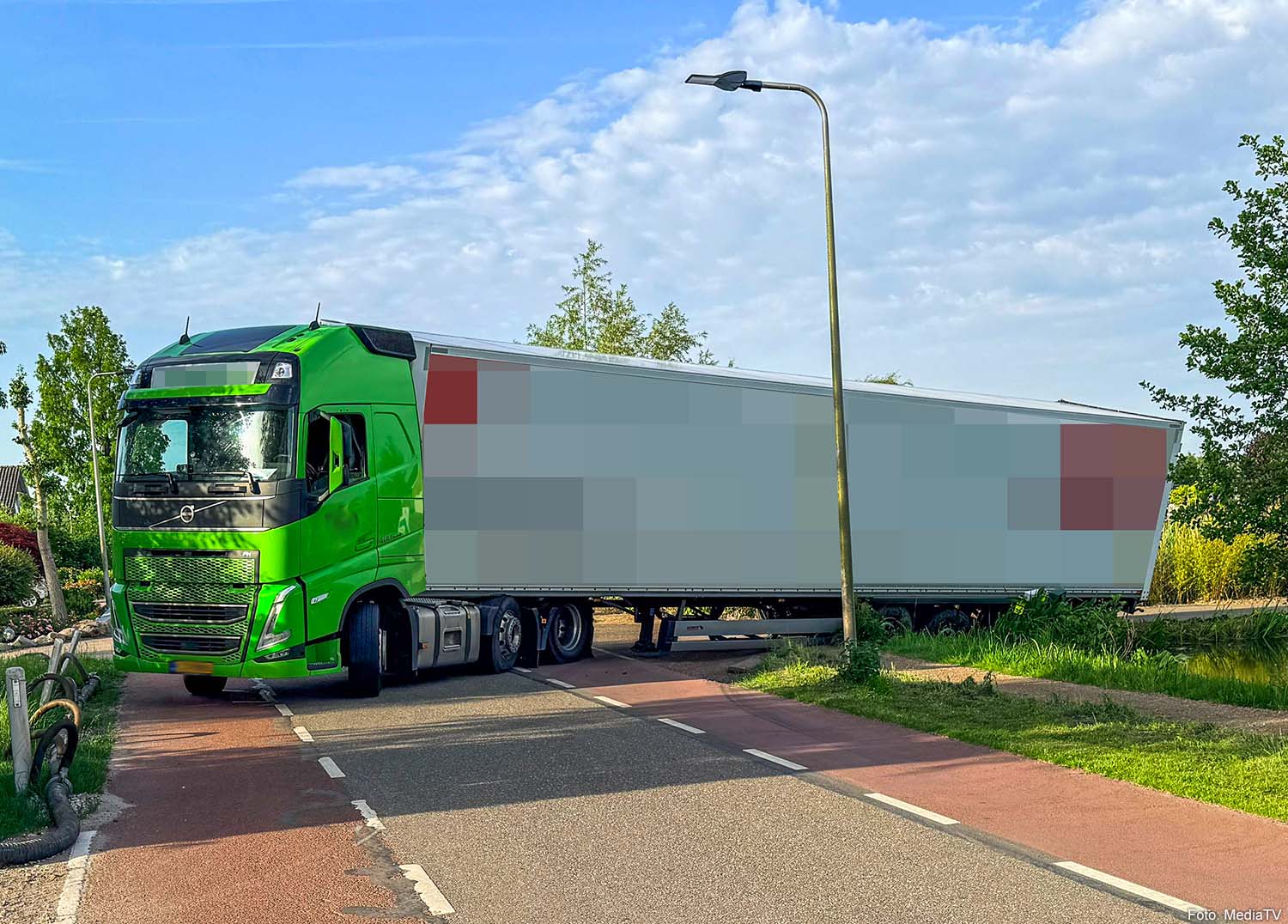 Vrachtwagen met lading potgrond zakt weg in berm en blokkeert weg in Boskoop